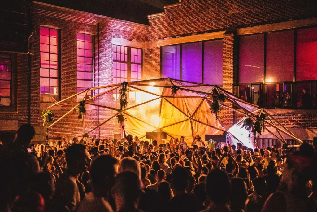 Brick industrial event venue illuminated by warm lights at dusk for a Halloween party in Detroit